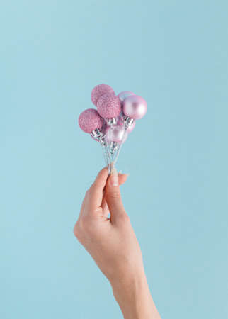 A woman's hand holds New Year's balls like flying balloons. Christmas concept.