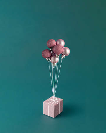 New Year's balls tied like balloons trying to lift a gift. Christmas concept.の写真素材