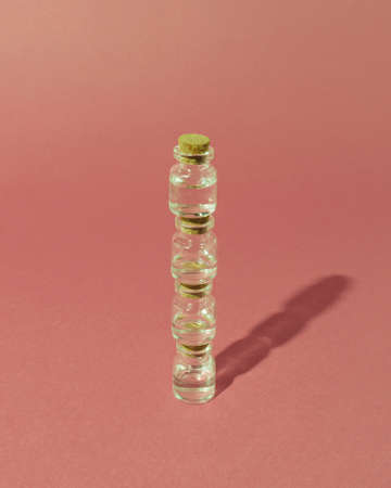 Glass bottles lined up on a pastel pink backgroundの写真素材
