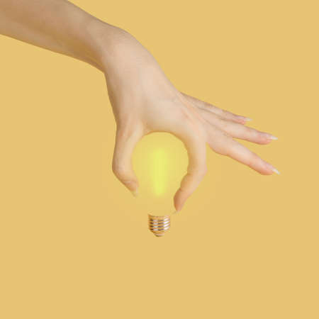 The hand makes the shape of a light bulb on a yellow background.