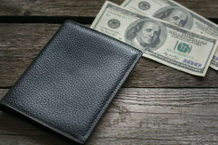 Black wallet and american dollar on wooden board.の写真素材