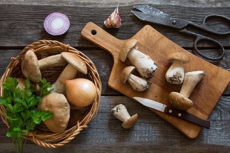 Fresh white mushrooms in basket and ingredients for mushroom's cream-soup on a rustic wooden board, overhead view.の写真素材