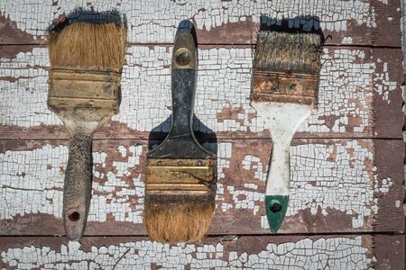 old used brushes against the background of an old dried paintの写真素材