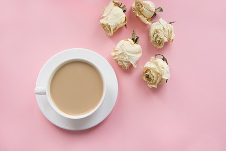 Still life of cup of coffee with milk with dry white roses around on pink background.の写真素材