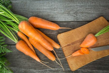 Fresh organic carrots with green tops on wooden table, closeup. Top view. Cooking.の写真素材