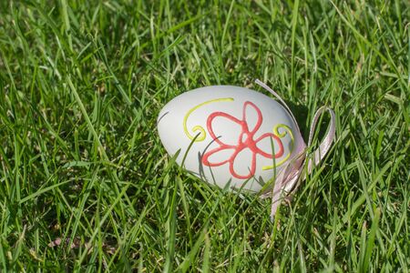 Easter painted eggs with ribbon on green grass.の写真素材