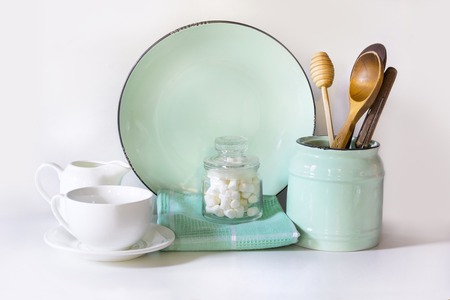 Crockery, tableware, utensils and other different white and turquoise stuff on white table-top....