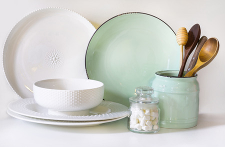 Crockery, tableware, utensils and other different white and turquoise stuff on white table-top. Kitchen still life as background for design. Image with copy space.の写真素材
