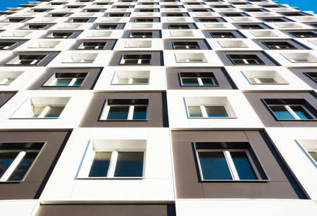 Modern and new apartment building. Photo of a tall block of flats with balconies in Moscow against a blue sky.の写真素材