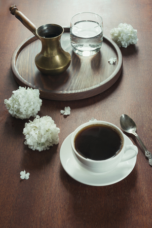 Cup of black coffee with copper cezve and water in a glass on wooden tray in vintage style. View from above.の写真素材