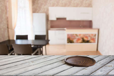 Blurred and abstract kitchen background. Empty wooden tabletop with cutting board  and defocused modern kitchen for display or montage your products.の写真素材