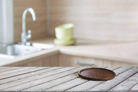 Blurred and abstract kitchen background. Empty wooden tabletop with cutting board  and defocused modern kitchen for display or montage your products.の写真素材