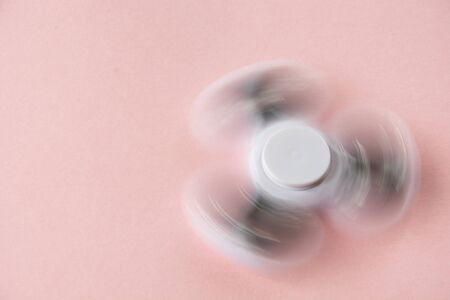 Fidget white finger spinner stress. Flat lay on pink.の写真素材