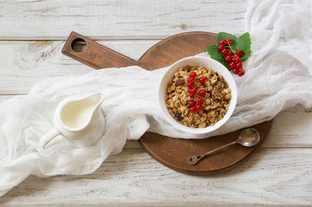 Summer healthy breakfast from muesli and milk jug with decor of a red currants on wooden rustic table. Top view.の写真素材