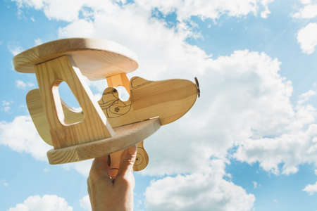 Toy airplane in hand and blue cloudy sky as background.の写真素材
