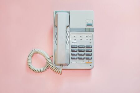White office telephone on pink background. Concept.