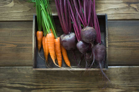 Harvest fresh vegetables from carrot, beetroot, onion, garlic on old wooden board. Top view, rustic style. Autumn still life. Gardening. Copy space.の写真素材