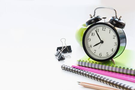 Colorful school supplies, book and alarm clock on white background. Close up. Back to school.