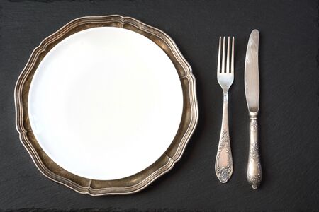 Vintage dish with silverware on slate background, with copy space for your menu or recipe. Table place setting. Top view.の写真素材