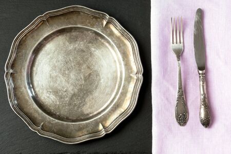 Vintage metal dish with silverware on slate background, with copy space for your menu or recipe. Table place setting. Top view.の写真素材