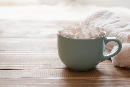 Blue cup of hot chocolate with marshmallow on windowsill. Weekend concept. Home style.