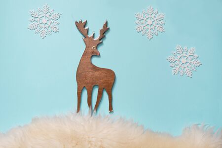 Figurine of a wooden Christmas deer on a blue background with snowflakes. Chistmas concept. Flat lay. Top view.の写真素材