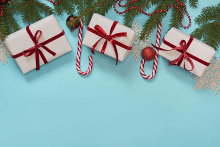 Christmas creative gift box wrapped with red ribbon, pack paper and a workspace composed on blue...