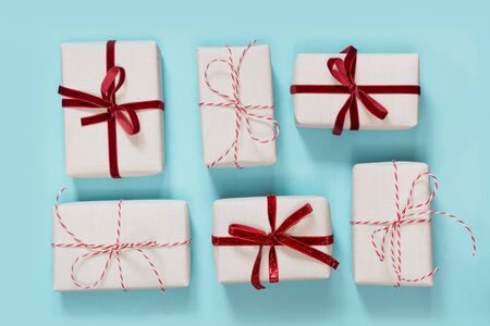Several Christmas gifts wrap in decorative paper with red bow laing on blue background. Flat lay. Top view.の写真素材