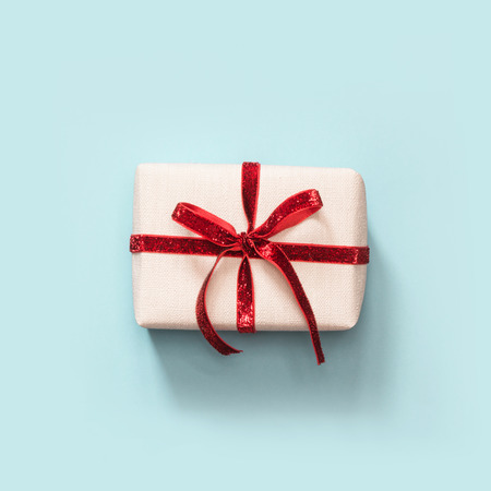 Gift with red ribbon on blue surface. Top view. Square image.の写真素材