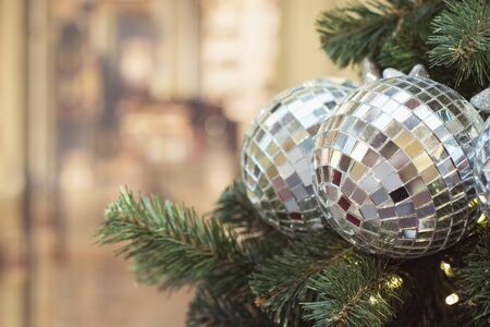 Christmas tree with holiday silver disco balls and lights with copy space on blurred bokeh background in interiors. Close up.の写真素材