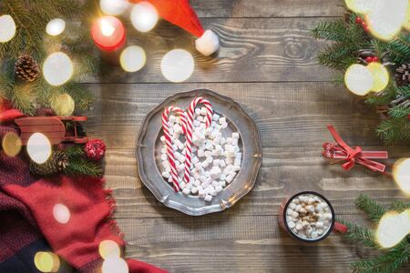 Christmas composition of wreath, checkered pleid, cup of coffee on wooden board. Flat lay. Top view. Copy space. Chocolate bar.の写真素材