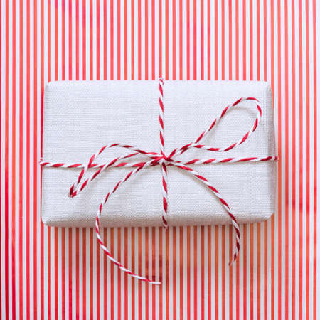 Christmas gift with red ribbon on stripes surface. Top view. Square image.の写真素材