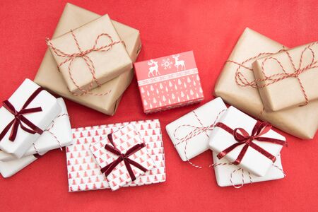 Christmas gifts wrapped in ornament paper and decorative red rope ribbon on red surface. Creative...