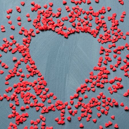 Valentines card concept with sweet red hearts sprinkling on gray background. Copy space. View from...