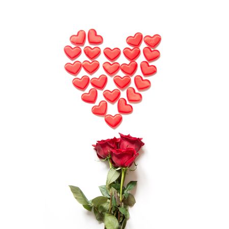 Red hearts as shape and bouquet of red roses on white. Top view. Valentine's card concept. Square image.の写真素材