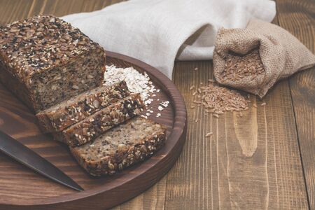 Fitness bread. Cut with slices and whole grain bread on a wooden board. A loaf of fresh rustic whole...