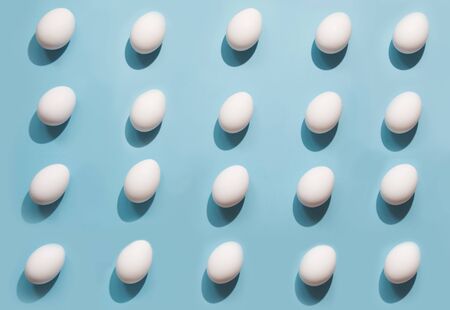 Organic white eggs on blue background. Abstract pattern. Eggs in isometric.の写真素材
