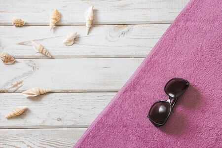 Beach towel and summer accessories on white wooden background. Travel concept. View from above. Blank mock up for advertising or packaging.の写真素材