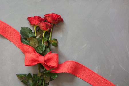 Bouquet of red roses and red ribbon on gray background. Valentine's card. Close up. Copy space.の写真素材