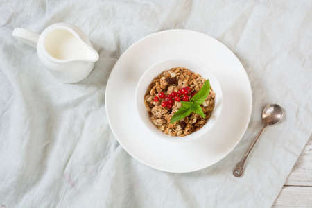 Summer healthy breakfast of granola, muesli with milk jug with red currant decor on light wooden board. Top view.の写真素材