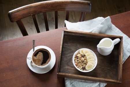 Healthy breakfast. Cup of black coffee, homemade oatmeal granola and nuts in interior. View from...