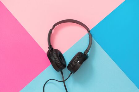 Modern style black headphones on the pink blue background. Top view.の写真素材