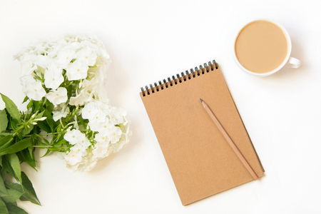 Coffee with milk, phlox flower, scretch-book on white table from above. Female working and creative desk. Hygge breakfast. Mockup. Flat lay.の写真素材