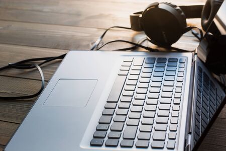 Headphones and laptop keyboard on wooden board. Closeupの写真素材