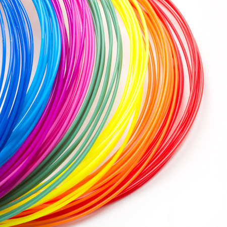 Colorful rainbow plastic filaments for 3D pen laying on white background. New toy for child. Close up.の写真素材