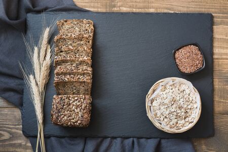 Fitness bread. A loaf of fresh rustic whole meal rye bread with wheat, sliced on a black slate dish...