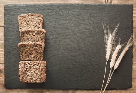 Fitness wholegrain rye bread. Loaf of sliced rye bread with seeds on black slate dish. Top view. Copy space.の写真素材