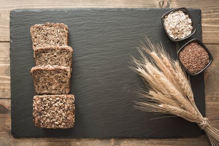 Fitness wholegrain rye bread. Loaf of sliced rye bread with seeds on black slate dish. Top view....