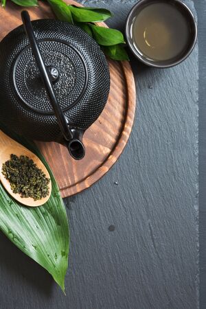 Green tea on black slate background. Ceremony. Black teapot and bowl with green tea. Top view with copy space.の写真素材
