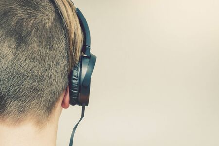 Young blond guy listening to music by headphones. Isolated. Close up.の写真素材